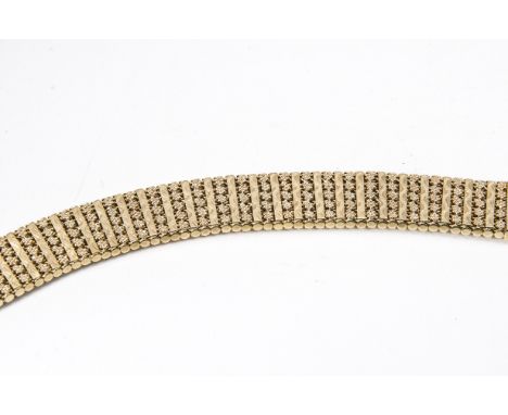 A contemporary 9ct gold cuff bracelet, the baton links in solid setting decorated with wavy engine turning, alternately set w