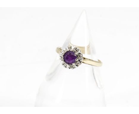 An 18ct gold amethyst and diamond cluster ring, the circular mixed cut amethyst surrounded by eight cut diamonds in illusion 