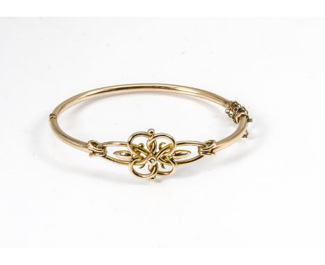 An Edwardian gold bangle, with hinged middle section, barrel clasp with safety chain decorated with stylised knot design, 10g