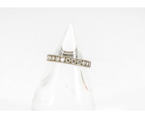 A diamond full eternity ring, the brilliant cuts in channel four claw setting with an engraved outer shank in white metal, po
