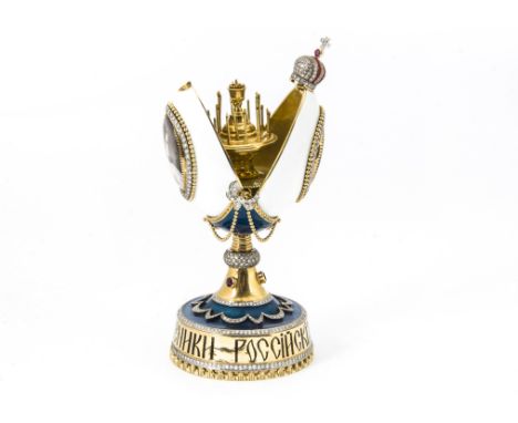A contemporary fine Russian gold gem set and enamelled egg on stand,  the white enamel and gold egg opening to reveal several