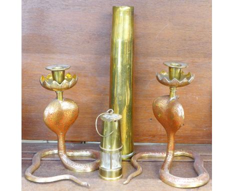 Two brass candlesticks in the form of cobras, a miniature miners lamp and a brass shell