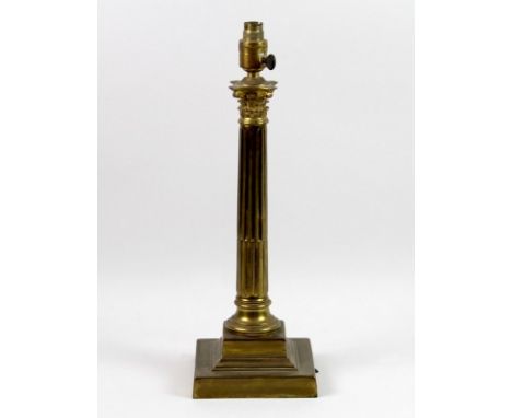 A brass table lamp, circa 1960, with Corinthian column, with a red shade, 48 by 44cm high.