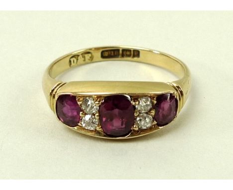 A Victorian Celtic revival 18ct gold, ruby and diamond ring, the central oval cut ruby flanked by two smaller rubies, divided