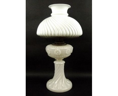 A Victorian milk glass paraffin lamp, the reservoir with raised repeated sunflower pattern, the shade and stem with gadrooned