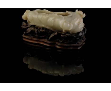 CARVED WHITE JADE BRUSH WASHER, QING DYNASTY, 19TH CENTURY, form a lily pad, raised on a carved wood stand, 10cm wide