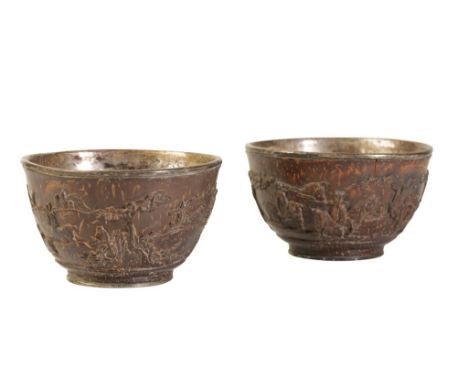 FINE PAIR OF SILVER MOUNTED CARVED COCONUT TEA BOWLS, KANGXI PERIOD, the sides finely carved with deer within a continuous la