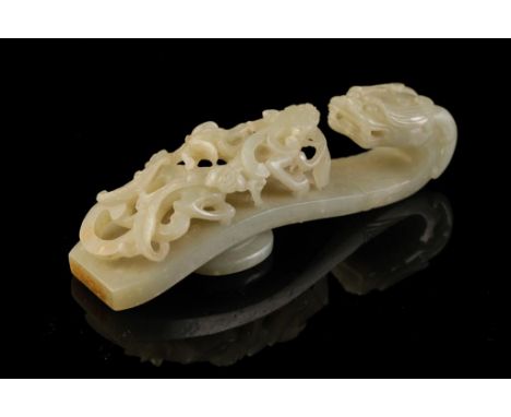 CELADON JADE BELT HOOK, QING DYNASTY, carved with a horned dragon forming the hook, and a chilong striding on the arched shaf