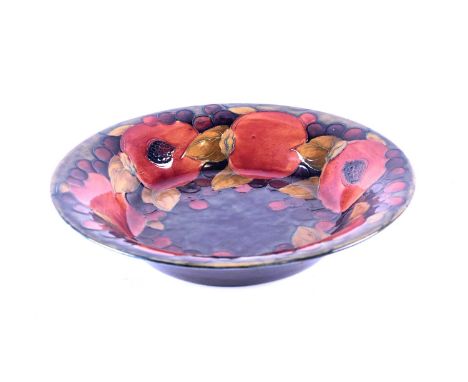 A William Moorcroft 'Pomegranate' bowl, circa 1930, the bowl decorated with leaves and berries against a shaded blue ground, 