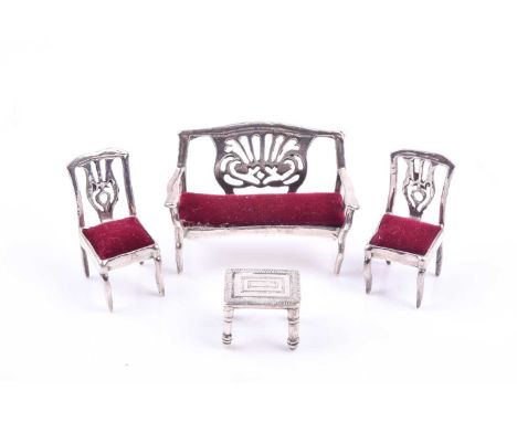 A sterling silver novelty miniature salon set, comprised of sofa, two chairs, and a table, sofa 4.7 cm wide.