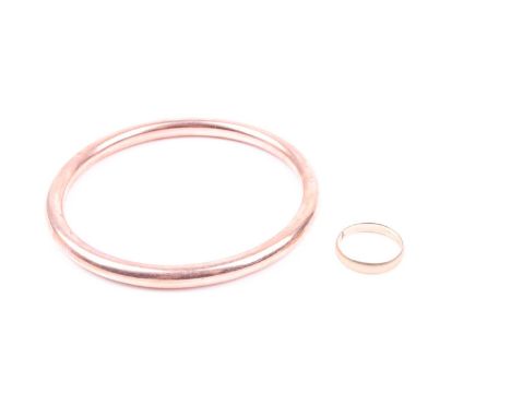 A 9ct rose gold hollow bangle, internal diameter 7.2 cm, together with a yellow metal band ring, unmarked, engraved 13 1879, 