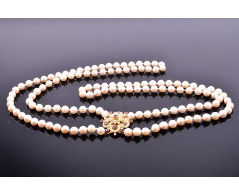 A double strand cultured pearl necklace, with gilt metal, pearl, and ruby floral cluster clasp, clasp 3.2 cm long, pearls 7mm