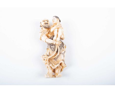 A Japanese ivory netsuke, late Meiji/Taisho, carved as a man holding a young boy in his arms, the boy holding a peach, possib