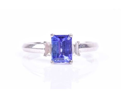 A platinum, diamond, and tanzanite ring, set with a mixed rectangular-cut tanzanite, approximately AAA grade colour, flanked 