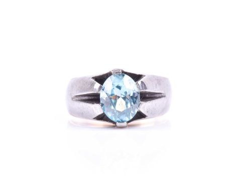 An unusual gilt, steel, and zircon ring, in the Victorian style, set with a mixed oval-cut light blue zircon, claw set, the e
