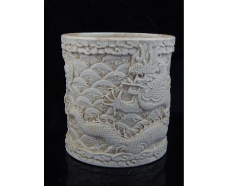 Chinese white ceramic relief carved brush pot, the dragon chasing the pearl above the cream sea with blue eyed fish leaping f