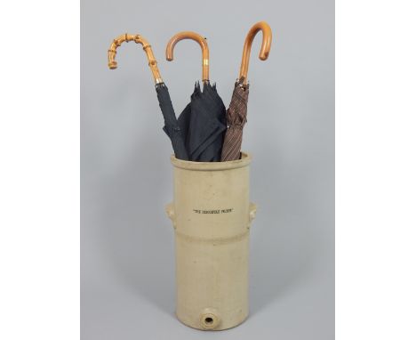 Victorian earthenware water filter now as a stick stand holding assorted umbrellas, one with integral pencil to handle