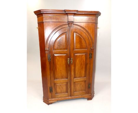 Georgian mahogany and string inlaid corner cupboard, dentil frieze above arched panelled door enclosing three shelves above t