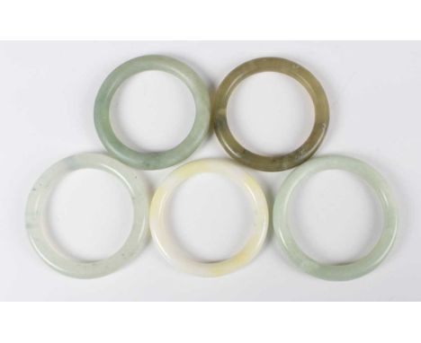 A group of five Chinese jade and hardstone bangles, 20th century and later, four of various green tones, the other of pale ye