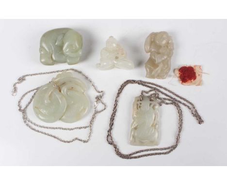 A group of four Chinese carved pale celadon jade pendants, late Qing dynasty and later, including one carved as a boy, height