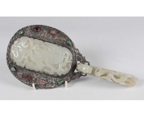 A Chinese pale celadon jade and plate mounted hand mirror, mid to late Qing dynasty, the plated oval mirror back cast in reli