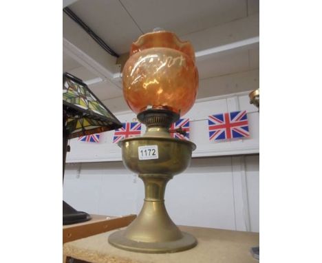 A brass oil lamp with amber glass shade.