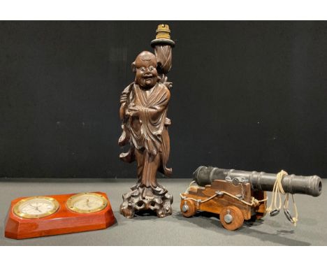 A Chinese carved hardwood figural lamp; a desk cannon; a mahogany and brass desk top combination clock and barometer (3) 