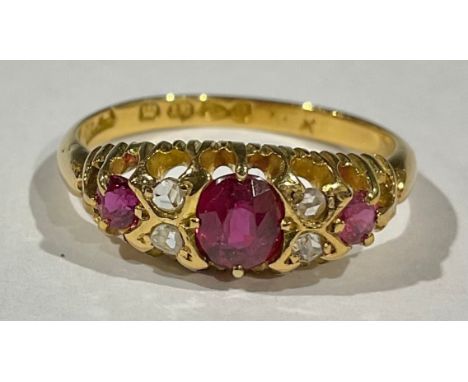 An 18ct gold ring set with three graduated faceted rubies, interspersed with four diamond chips, size K, marked 750, Chester 