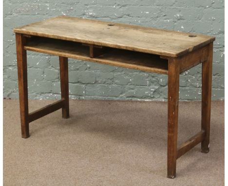 A double oak school desk raised on tapering square cut legs with under desk shelf. (width 101.25cm, depth 41.75cm, height 63.