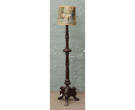 A extensively carved mahogany standard lamp raised on lion head tripod base.