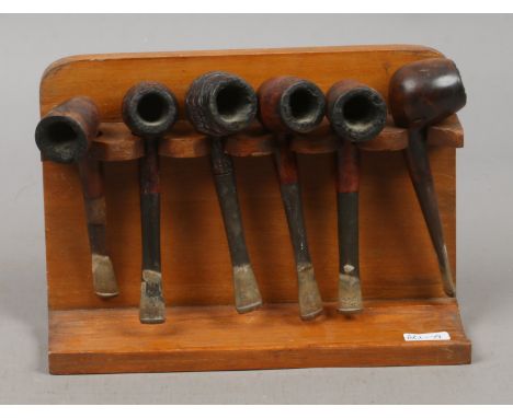 A vintage light oak smokers pipe rack with six pipes.