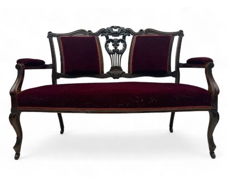 Late Victorian dark oak framed sofa, the backrests, seat and padded arms upholstered in deep red fabric, carved crest rail wi
