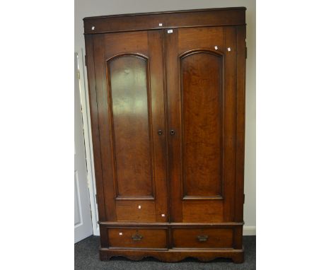 A Victorian mahogany and oak double wardrobe, two arched panel doors enclosing bisected interior with shelving, two short dee