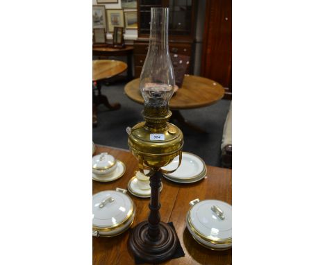 A Victorian brass and oak oil lamp, brass reservoir, turned oak column and foot.