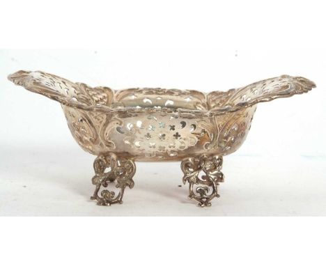 Late Victorian silver bonbon dish of oval form, pierced and decorated with flowers, scrolls etc and supported on four decorat
