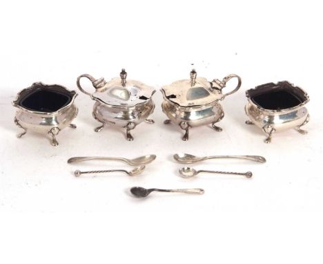 A four piece hallmarked silver condiment set comprising two hinge lidded mustards, two open salts (with four blue glass liner