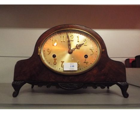 A mid-20thC walnut cased dome topped mantel clock with silvered dial and Arabic numerals, raised on squat carved cabriole sup