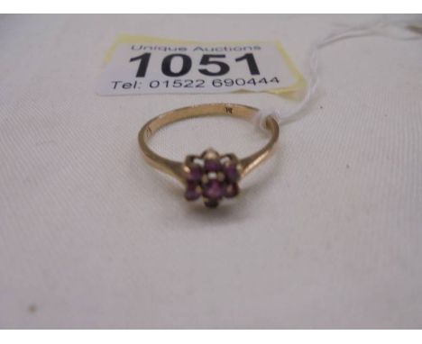 A ruby stone set ring in a cluster design, hall marked London 1965, size O half, 1.4 grams.