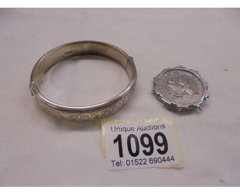 A silver bangle and a silver Victorian coin brooch.