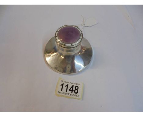 An early 20th century silver inkwell with enamel top and glass insert.