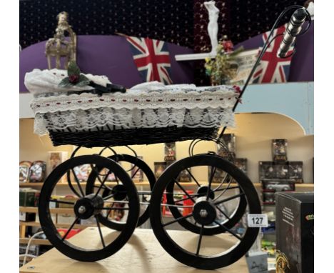 A vintage style wicker dolls pram on wooden wheels