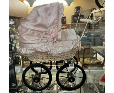A vintage wicker dolls pram with pink covering