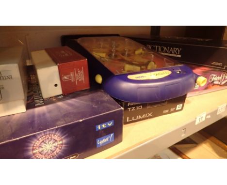 Shelf of mixed games including Trivial Pursuit Pictionary pinball game etc