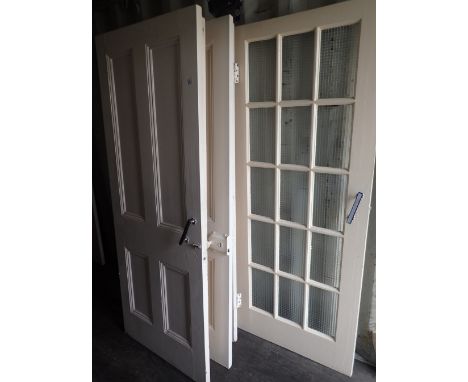 Six matching four panel pine doors painted white and one twelve pane glass door 
