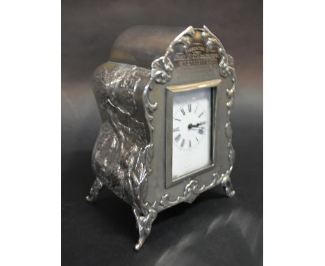 A Victorian Silver Table Clock, decorated in relief with figures and of shaped form with scroll feet with French movement, th