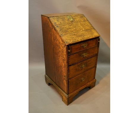 A George III Oak Bureau of small proportions, the fall front above four drawers with brass handles raised upon bracket feet, 
