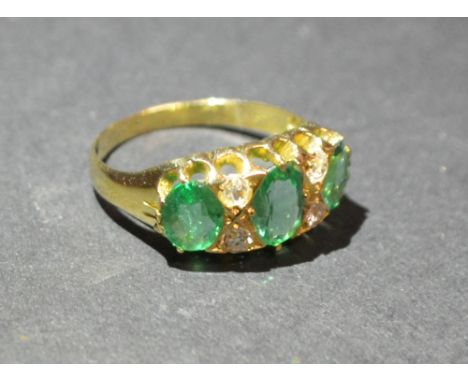 An 18ct. Yellow Gold Emerald and Diamond Three Stone Ring, set with three emeralds interspaced with diamonds within a pierced