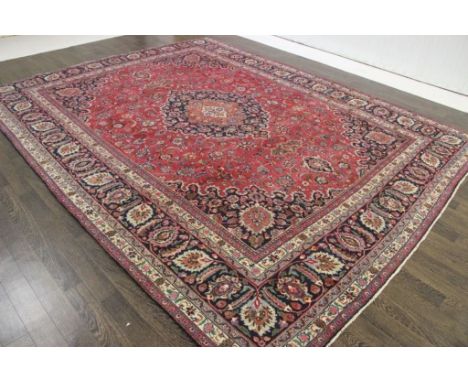 A North West Persian Woollen Carpet, with a central medallion amongst an all over design upon a red, blue and cream ground wi