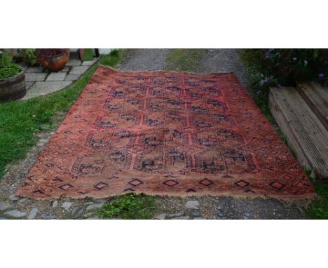 A North West Kashmiri Carpet with three rows of six guls upon a red ground within multiple borders, 328 x 255 cms