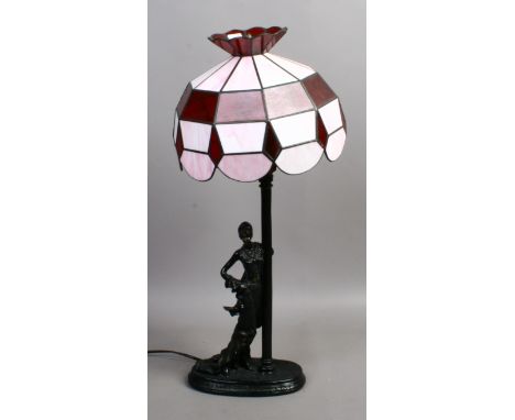 A Tiffany style tablelamp with ruby and pink glass shade raised on an Art Deco figure of a woman.
